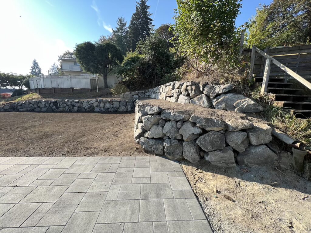 Seattle back yard with big space for entertaining. Custom pavers and rockery wall.