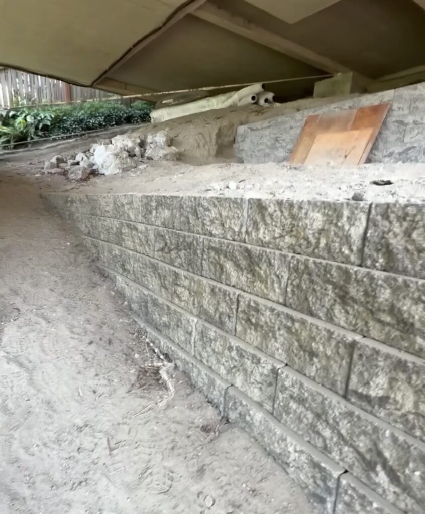 Curved lower-tier block retaining wall stabilizing a terraced hillside yard in Seattle, WA